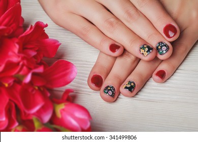 Red Nail Art With Printed Flowers On Light Wooden Background