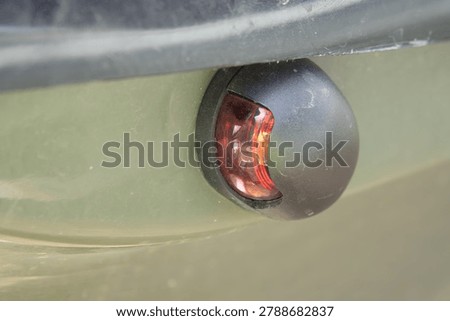 A red navigation light on the bow of a olive drab boat