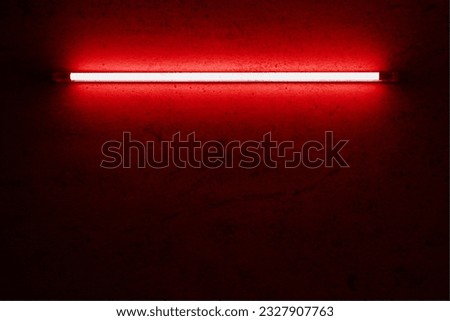 red neon light bulb on cement wall.
