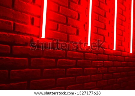 Red neon lines on brick wall in night club. Place for text.