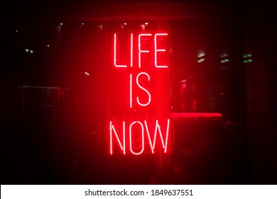 Red neon sign life is now. Glow quote about live and self motivation. Here and now abstract concept.