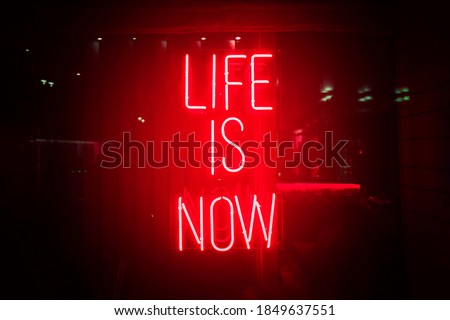 Red neon sign life is now. Glow quote about live and self motivation. Here and now abstract concept.