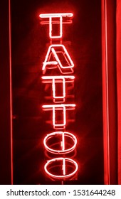 Red Neon Signboard Of The Word.Tattoo Sign, Neon Sign In A Tattoo Shop Window. Red Information Sign, View From Outside Into A Store. 