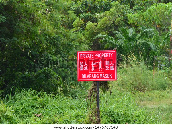 A red no\
entry private property sign board in three languages chinese\
english malay very common sight in\
Malaysia