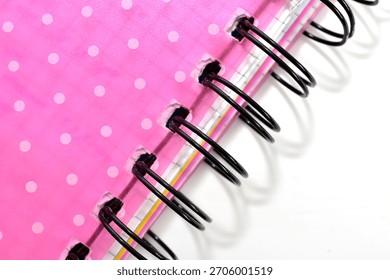 A red notebook with a wire spring binding lies on a white table.