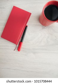 Red notepad, marker and cup on a wooden gray table. Top view, Copy space