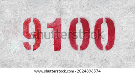 Red Number 9100 on the white wall. Spray paint. Number nine thousand one hundred.