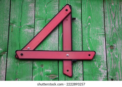 Red Number Four Sign From Car Reflector Triangle On Green Wooden Wall As The House Number. 