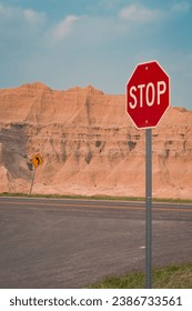 A red octagonal STOP sign is set against a background of a large stone bluff at the edge of a road