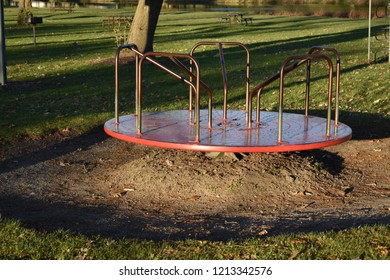 A Red, Old Metal Merry Go Round In A Park Playground