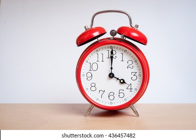 red old retro style alarm clock on wood table. Alarm clock shows four o`clock