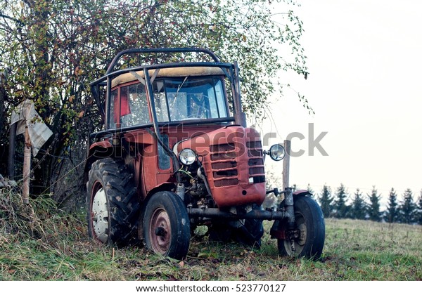Red old tractor on the\
field