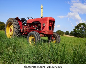 Red old tractor standing in a green field great agriculture background image with space for text graphics