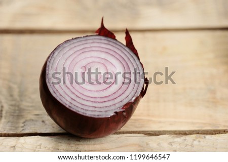 red onion bulb with cut on wooden background