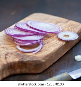 Red Onion Slices on wooden board with dark background