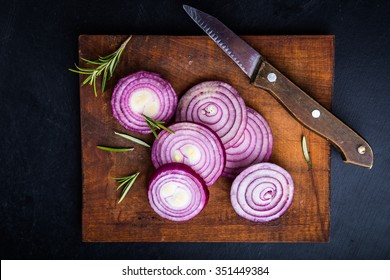 Red Onion Slices On Wooden Board With Dark Background