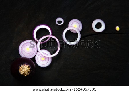 Red onion vegetables sliced on a black table. Red onion rings with spice closeup. top view.