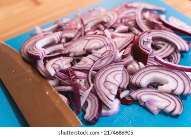 Red Onions Sliced With A Kitchen Knife, On A Turquoise Kitchen Mat.