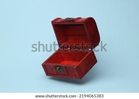 Red open pirate chest flying in antigravity on blue background with shadow. Levitation object in the air. Creative minimal layout