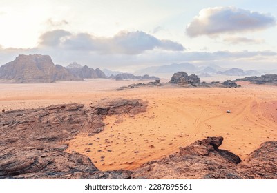 Red orange Mars like landscape in Jordan Wadi Rum desert, mountains background overcast morning, small vehicle distance for scale. This location was used as set for many science fiction movies - Shutterstock ID 2287895561