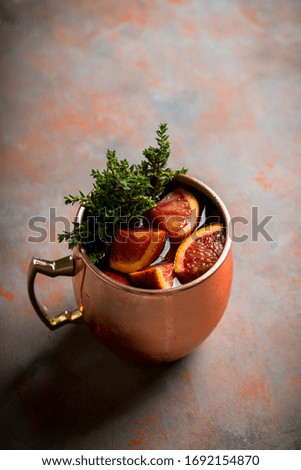 Red oranges cocktail in copper mug (variation of Moscow mule) on the wooden background. Selective focus. Shallow depth of field.
