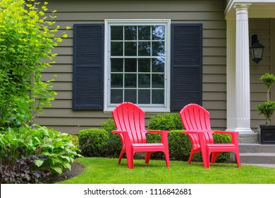 Red Outdoor Chairs On Green Grass Lawn Of House Manicured Front Yard