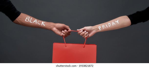 Red Packet Mockup In Hands Of Man And Woman With Black Friday Inscription On Dark Background, Panorama. Discount And Sale Concept