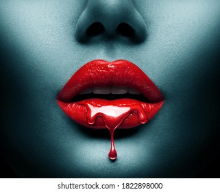 Red Paint dripping, lipgloss drops on sexy lips, bright liquid paint on beautiful model girl's mouth, Vampire. Halloween. Lipstick. Make-up. Beauty face makeup, close up. Isolated on black background