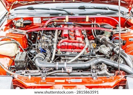 Red painted high-performance car engine bay showcasing horizontally opposed boxer engine, neatly arranged hoses, wires, and metallic parts emphasizing clean layout and vibrant aesthetics.