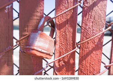 Red painted master key is locking on the steel and red wood fence. An old rustic key hang is left on the old construction.