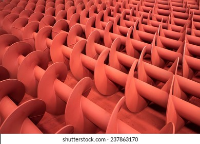 Red Painted Metal Screws For Industrial Screw Conveyors At A Paintshop.