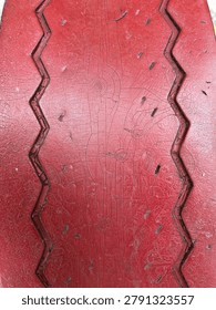 Red painted surface texture with zigzag carved pattern and scratches