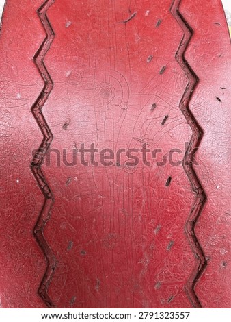 Red painted surface texture with zigzag carved pattern and scratches