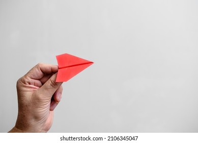 Red Paper Airplane In The Hands Of A Man