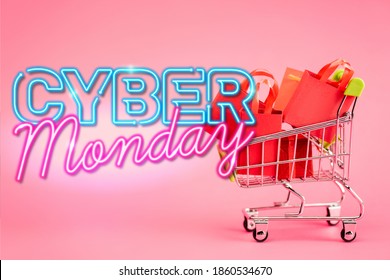 red paper bags in small shopping trolley near cyber monday lettering on pink