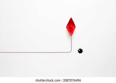 Red Paper Boat Changes Direction Against A Naval Mine On White Background. Risk, Threat Or Danger Avoidance In Business Concept.