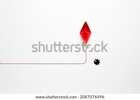 Red paper boat changes direction against a naval mine on white background. Risk, threat or danger avoidance in business concept.