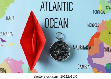 Red Paper Boat And Compass On World Map, Flat Lay