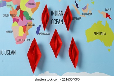 Red Paper Boats On World Map, Flat Lay