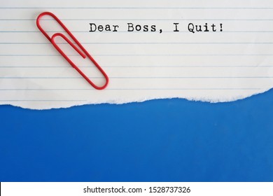 A red paper clip on a lined note paper with a written text DEAR BOSS I QUIT, concept of decision making to resign or quit job