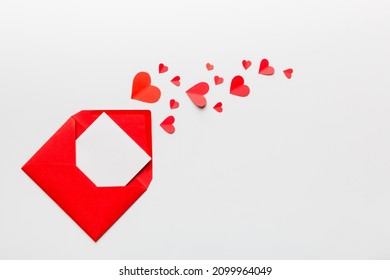 Red paper envelope with empty white card and heart on colored background. top view valentines day concept.
