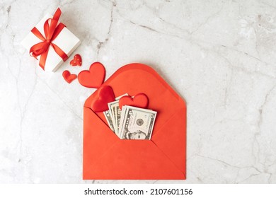 Red Paper Envelope With Money Dollars Bills. Flat Lay Of Gray Working Table Background With Valentine Gift, Letter, Heart Shape. Top View, Mock Up Greeting Card. Valentine's Day Budget