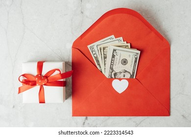 Red Paper Envelope With Money Dollars Bills. Flat Lay Of Gray Working Table Background With Valentine Gift, Letter, Heart Shape. Top View, Mock Up Greeting Card. Valentine's Day Budget