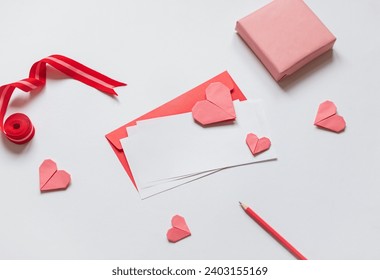 Red paper envelope with white blanks and pink origami hearts. Valentine's day concept card. Copy space - Powered by Shutterstock