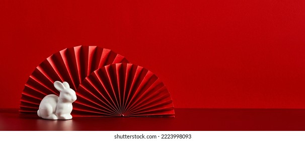 Red paper fans with figure of rabbit on red background. Chinese New Year holiday banner, Lunar New Year greeting card template. New Year of the Rabbit concept - Powered by Shutterstock