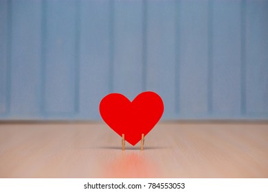 Red paper Heart of love with wooden clips on table with blue wooden background. Romantic symbol. Love concept