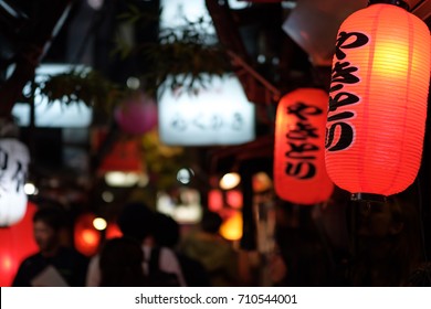 Red paper lanterns advertising chicken skewers in a dark alley in Tokyo at night.
The sign reads "Yakitori" in Japanese. - Shutterstock ID 710544001
