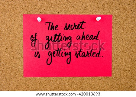 Red paper note with handwritten text The Secret Of Getting Ahead Is Getting Started pinned on cork board with white thumbtacks