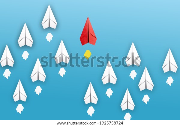 Red paper\
plane leading among a white planes on blue background. Business\
competition and Leadership\
concept