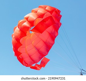 A Red Parachute Flies In The Blue Sky.